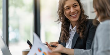 Business woman smiling at client as they look at investment graphs