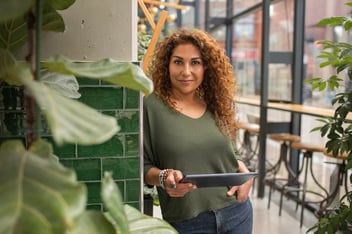 Business woman leaning against wall with tablet