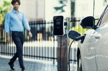 Employee walking towards charging electric vehicle in carpark
