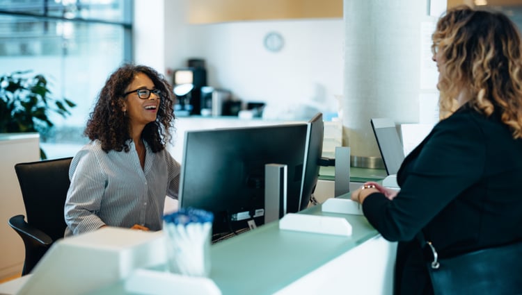 woman at a desk talking with another woman
