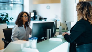woman at a desk talking with another woman