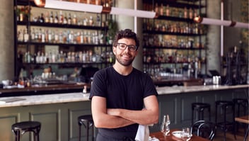 business owner smiling in front of restaurant bar