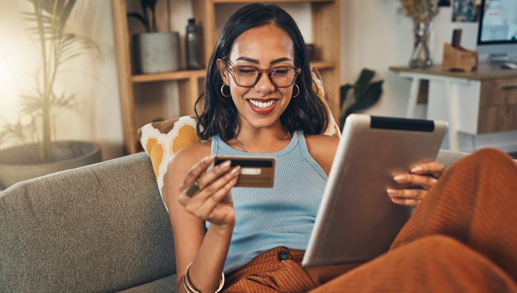 Smiling using credit card for ecommerce on digital tablet at home.