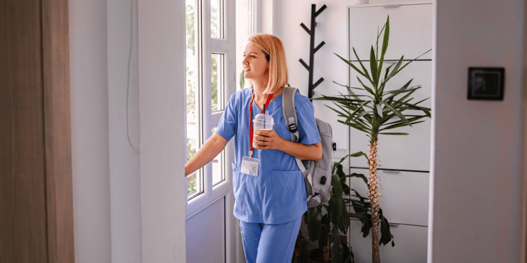 Female doctor with coffee looking out window