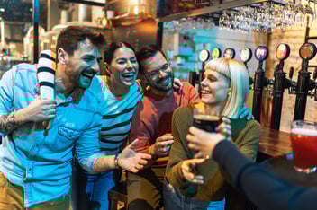A group of friends laughing together at a bar