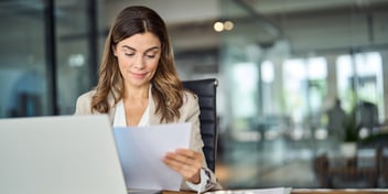 woman looking at paper sitting at desk