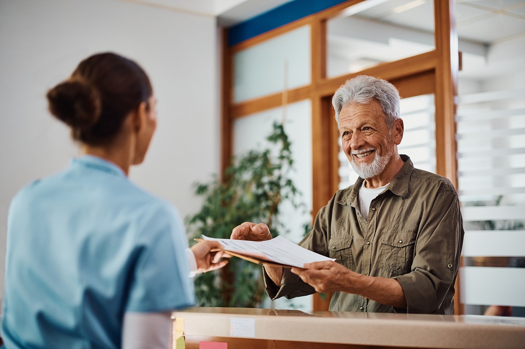 Patient smiling while handing paperwork to reception