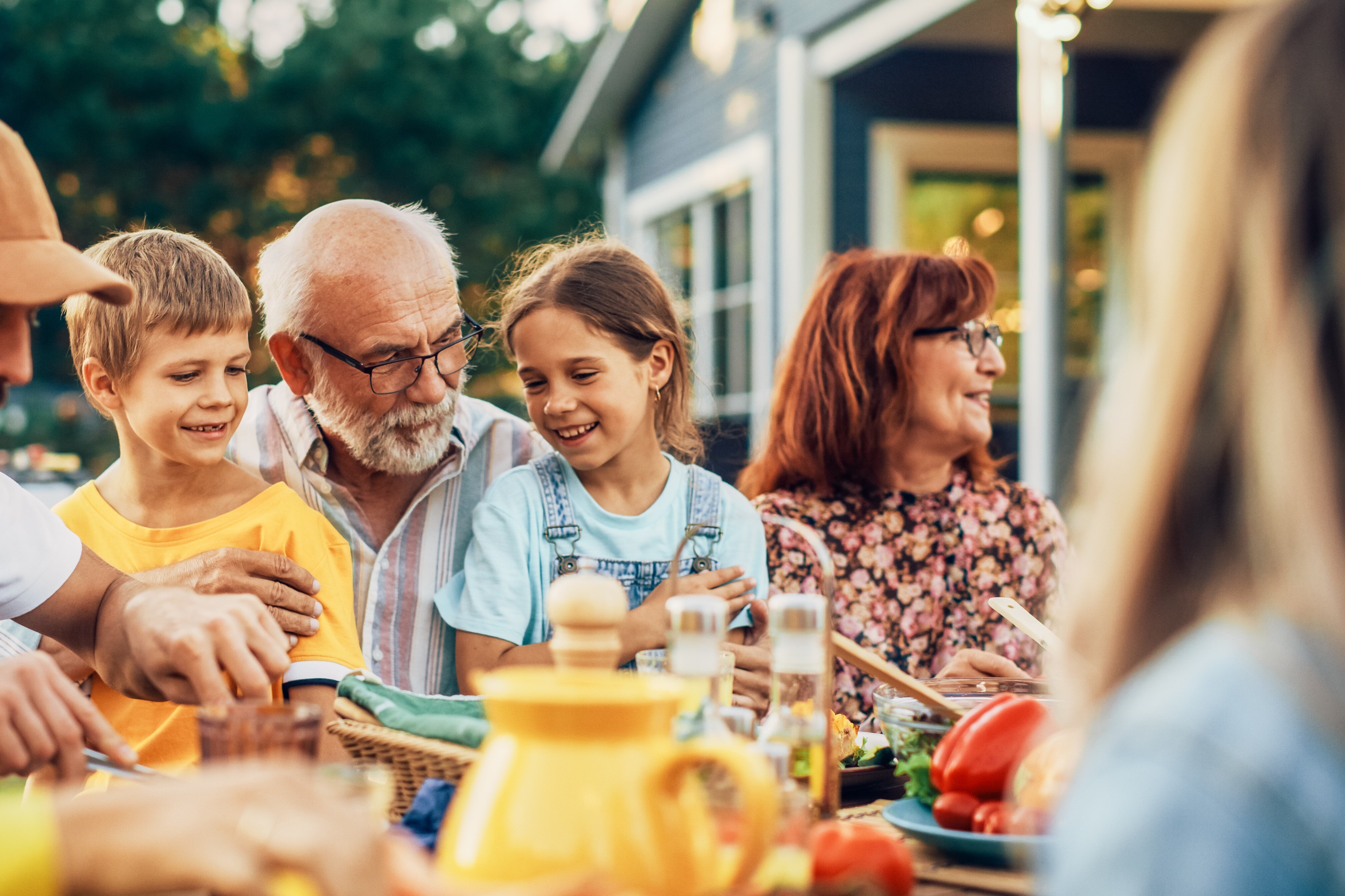 Family eating around an outdoor table together and laughing