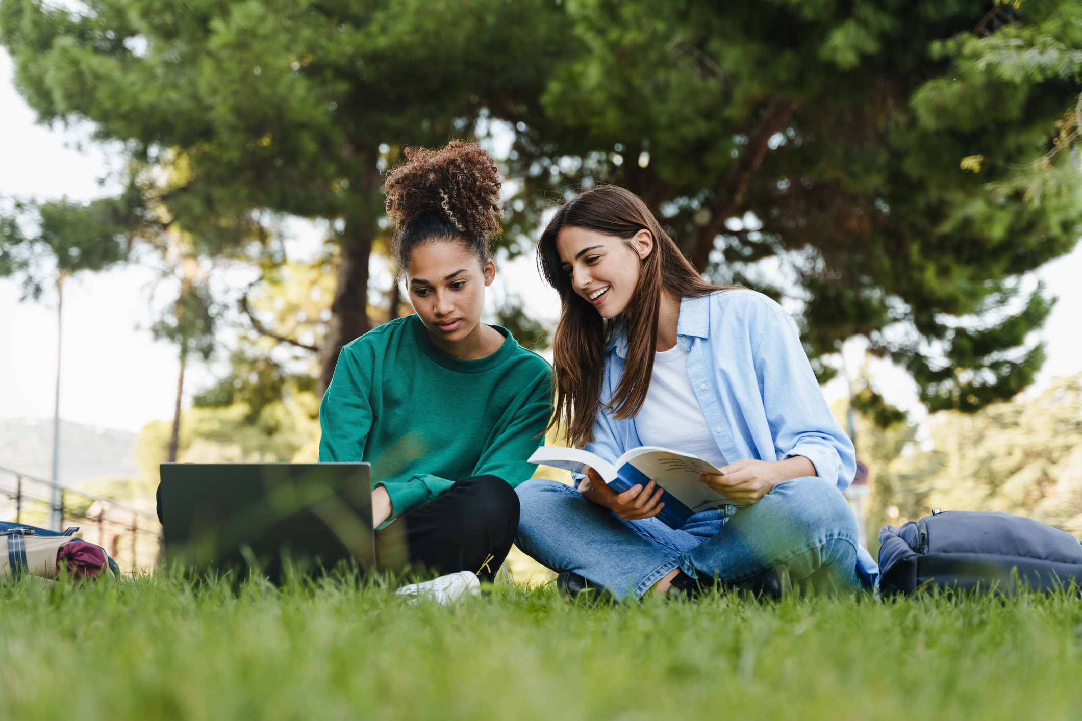 Two female first year university students studying together in a park
