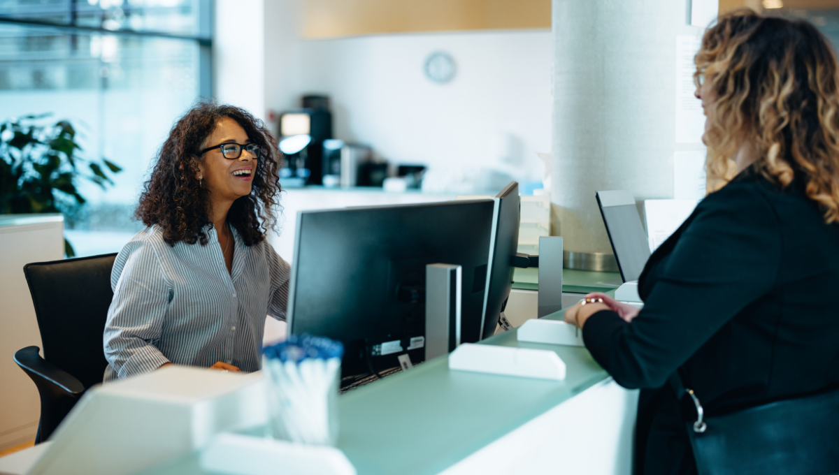 woman at a desk talking with another woman